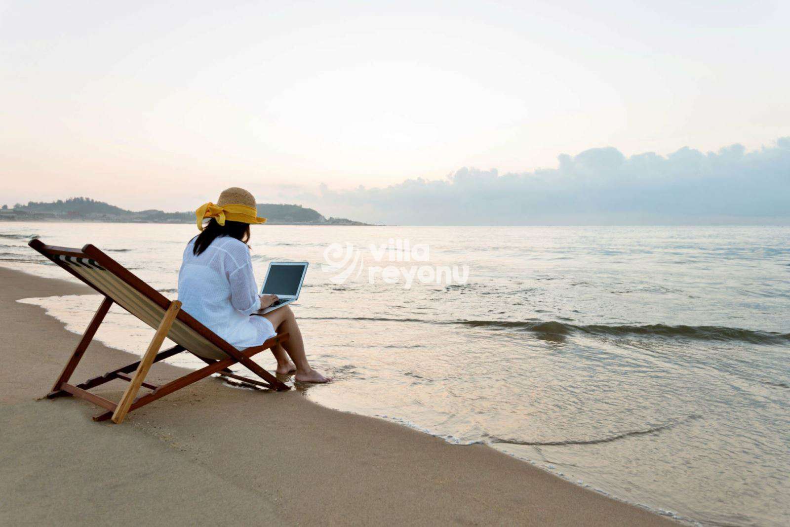çalış plajında laptopla şezlongda oturan bir insan